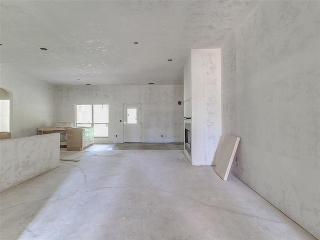 interior space with unfinished concrete flooring and a fireplace