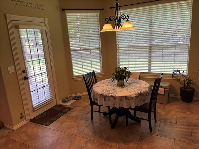 tiled dining room with a healthy amount of sunlight and a notable chandelier