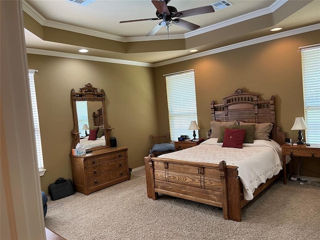 carpeted bedroom with a tray ceiling, multiple windows, ceiling fan, and ornamental molding