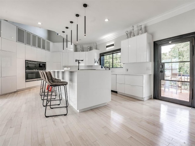 kitchen with white cabinets, a center island, hanging light fixtures, and a wealth of natural light