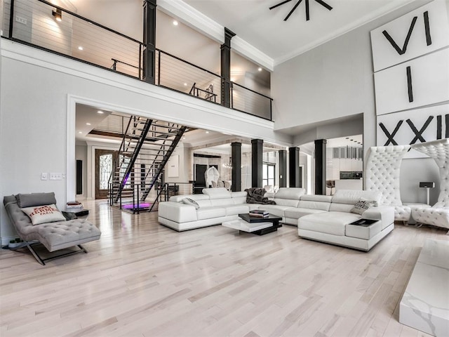 living room with crown molding, a high ceiling, and light hardwood / wood-style flooring