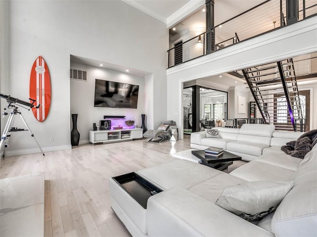 living room with wood-type flooring, ornamental molding, and a high ceiling