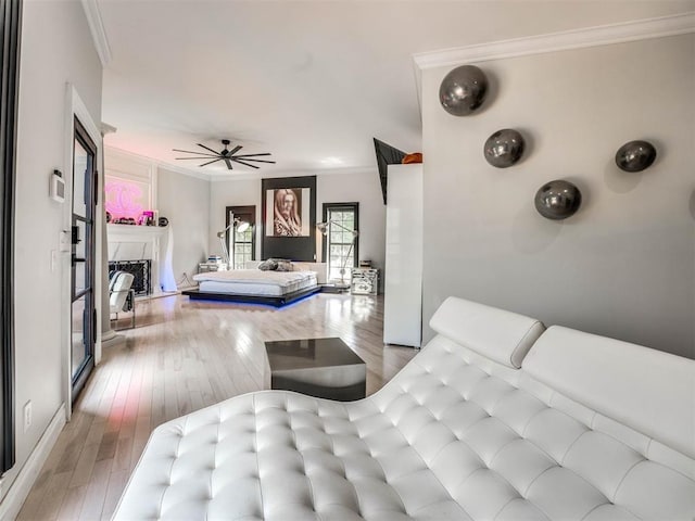 bedroom featuring a high end fireplace, light hardwood / wood-style flooring, and ornamental molding