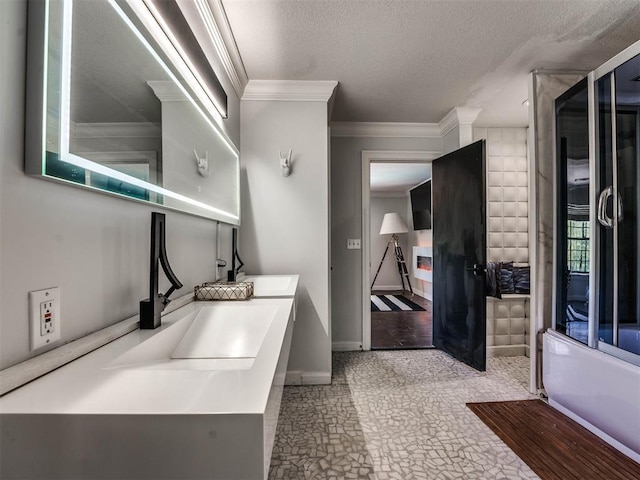 clothes washing area featuring sink, a textured ceiling, and ornamental molding