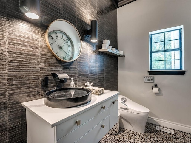 bathroom featuring tile patterned flooring, vanity, toilet, and tile walls