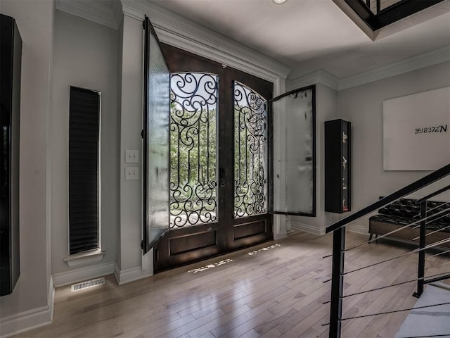 foyer entrance featuring french doors, ornamental molding, and light wood-type flooring