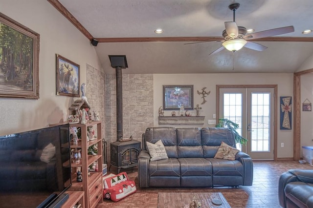 living room featuring hardwood / wood-style floors, a wood stove, ceiling fan, and lofted ceiling