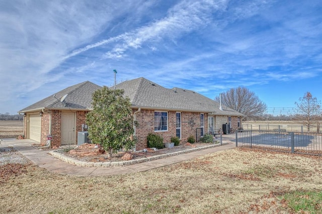 view of front of home with a garage, a fenced in pool, and central AC