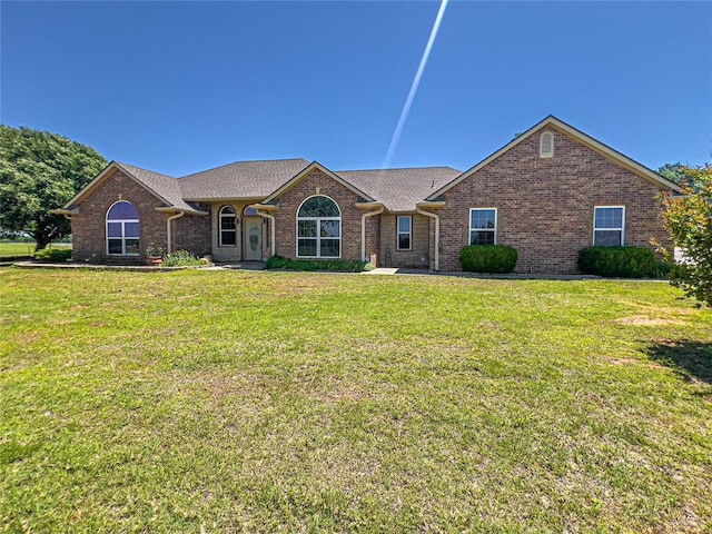 ranch-style house with brick siding, a front lawn, and a shingled roof