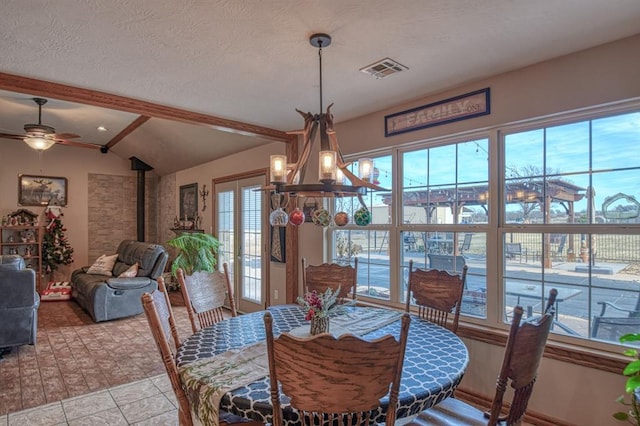 dining room with a ceiling fan, a wood stove, light tile patterned floors, and a textured ceiling