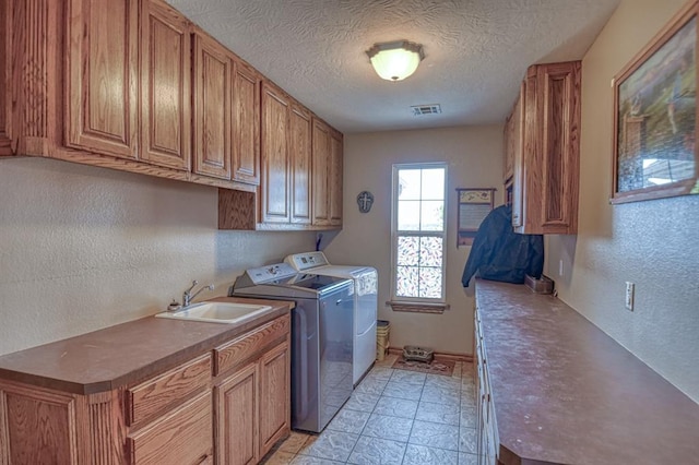 laundry area with independent washer and dryer, cabinet space, a textured wall, and a textured ceiling