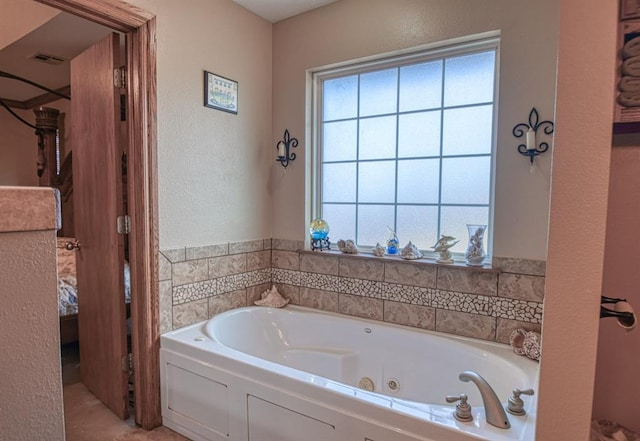 ensuite bathroom featuring a tub with jets