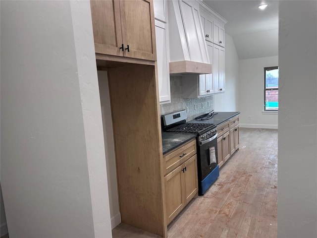 kitchen featuring gas stove, premium range hood, light hardwood / wood-style floors, light brown cabinetry, and tasteful backsplash