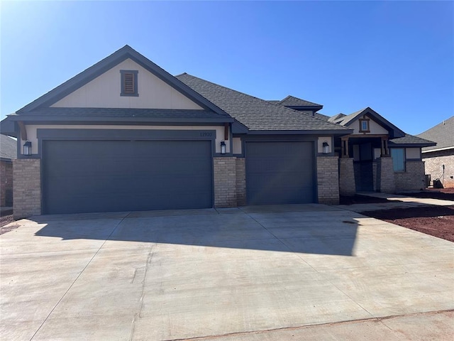 view of front of property with a garage, driveway, a shingled roof, and brick siding