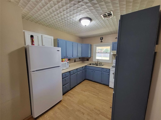 kitchen with blue cabinetry, white appliances, sink, and light hardwood / wood-style flooring