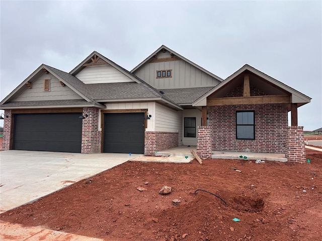 view of front of home featuring brick siding, a shingled roof, concrete driveway, an attached garage, and board and batten siding