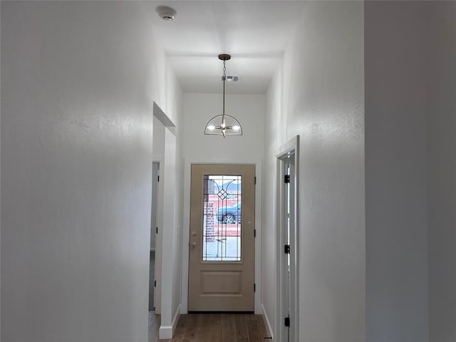 entryway featuring visible vents, a notable chandelier, baseboards, and wood finished floors