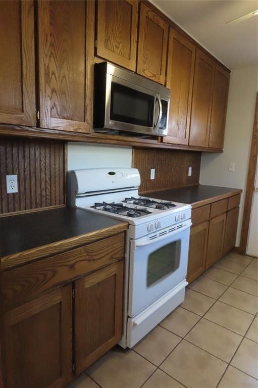 kitchen with white gas stove and light tile patterned floors