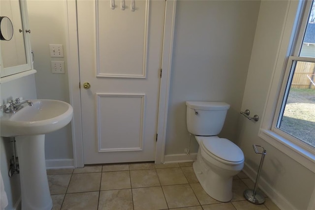 bathroom with toilet, a wealth of natural light, tile patterned flooring, and sink