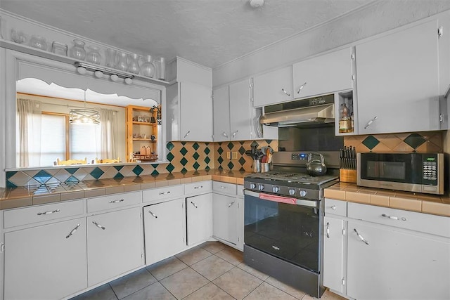 kitchen featuring white cabinets, black gas range, backsplash, and tile counters