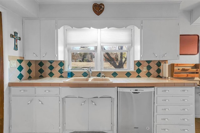 kitchen featuring backsplash, tile counters, sink, and stainless steel dishwasher