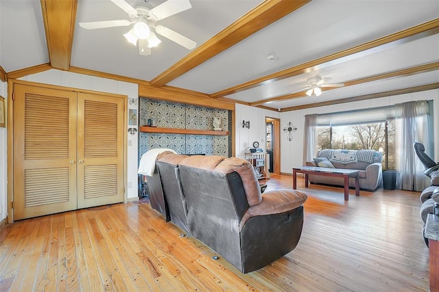 living room with beamed ceiling, light wood-type flooring, ceiling fan, and ornamental molding