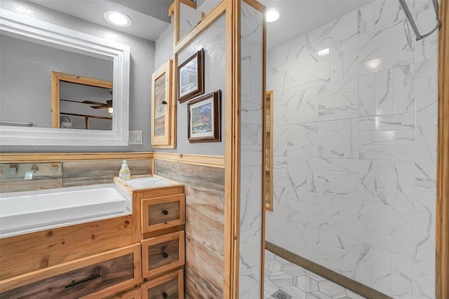 bathroom with vanity, tiled shower, and tile walls