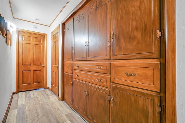 hallway with light wood-type flooring and ornamental molding