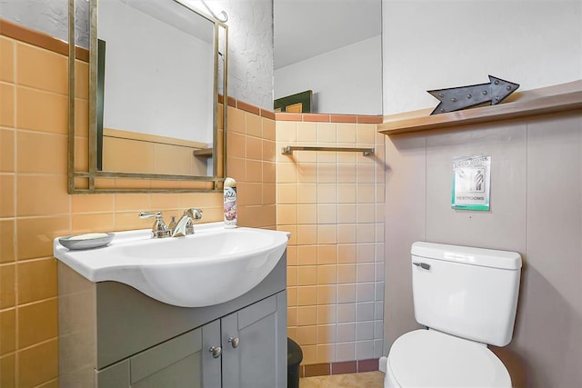 bathroom with vanity, toilet, and tile walls