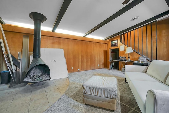 tiled living room with a wood stove, wooden walls, and beamed ceiling