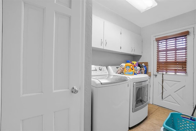 washroom with washing machine and dryer, light tile patterned floors, and cabinets