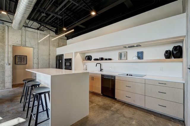 kitchen with a breakfast bar, black appliances, sink, a kitchen island, and concrete flooring