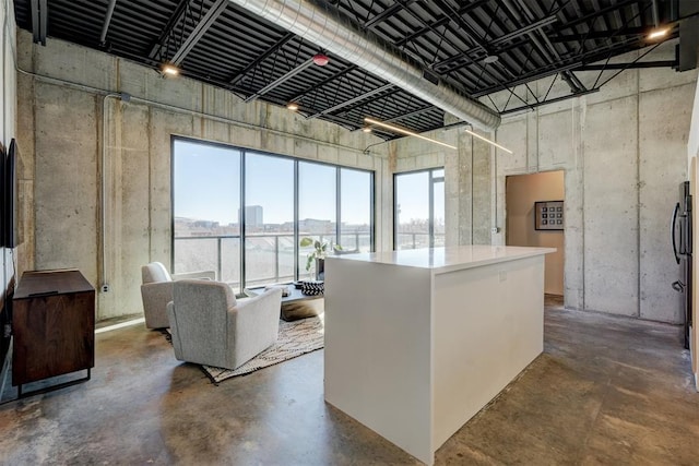 kitchen with a kitchen island, a high ceiling, and concrete floors