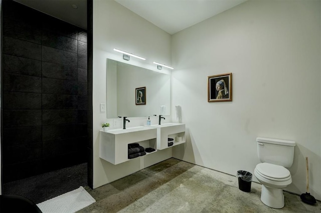 bathroom featuring tiled shower, toilet, and concrete flooring