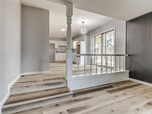 stairs featuring wood-type flooring, an inviting chandelier, and wood walls