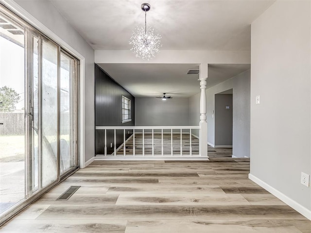 spare room with hardwood / wood-style floors and ceiling fan with notable chandelier