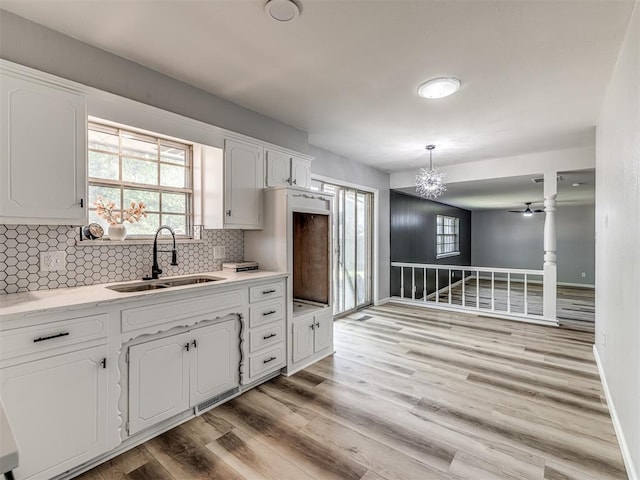 kitchen with backsplash, sink, pendant lighting, light hardwood / wood-style flooring, and white cabinetry