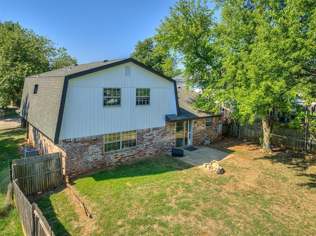 rear view of property featuring a lawn, a patio area, and cooling unit