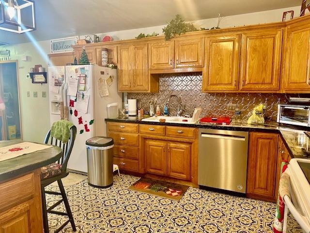 kitchen with stove, backsplash, sink, stainless steel dishwasher, and white fridge with ice dispenser