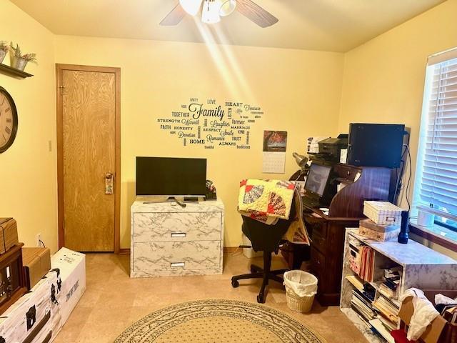 carpeted office space with ceiling fan and a healthy amount of sunlight