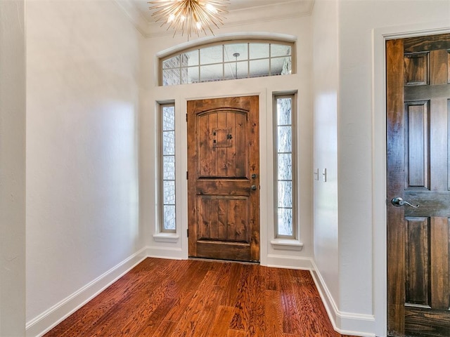 foyer featuring an inviting chandelier, crown molding, and dark wood-type flooring