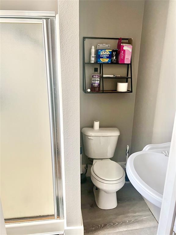 bathroom with hardwood / wood-style flooring, toilet, and an enclosed shower