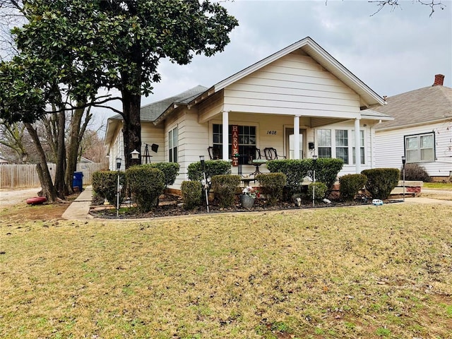 bungalow featuring covered porch and a front lawn