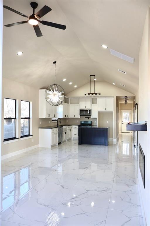 kitchen with white cabinets, ceiling fan with notable chandelier, hanging light fixtures, vaulted ceiling, and appliances with stainless steel finishes