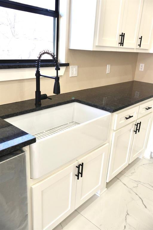 kitchen with dishwasher, white cabinetry, and sink