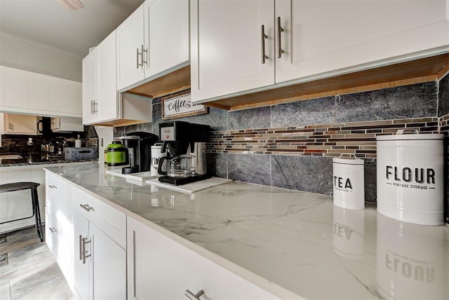 kitchen featuring light stone counters, white cabinets, and decorative backsplash