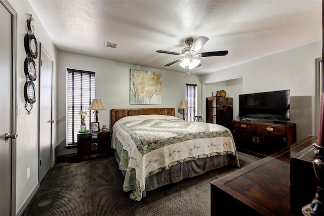 bedroom featuring ceiling fan, a textured ceiling, dark carpet, and visible vents