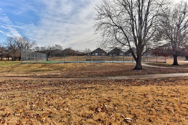 view of yard featuring a tennis court and fence