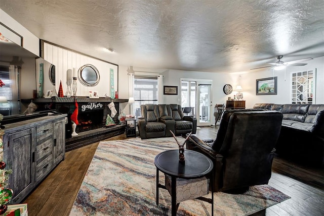 living room featuring ceiling fan, dark hardwood / wood-style floors, and a textured ceiling