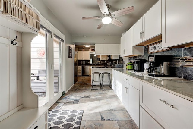 kitchen featuring ceiling fan, dishwasher, black refrigerator, tasteful backsplash, and white cabinets